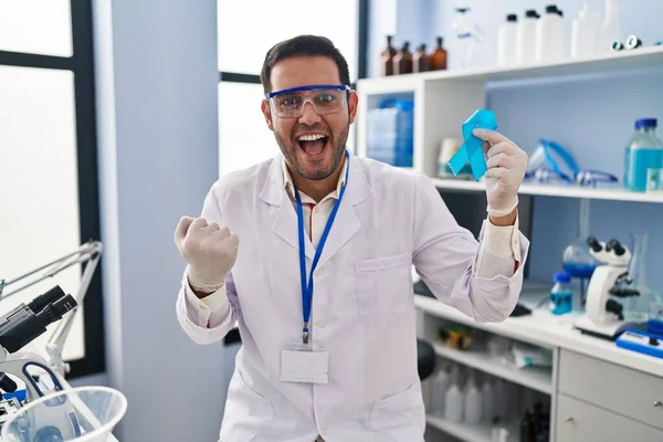 Young Hispanic Man Beard Working Scientist Laboratory Holding Blue Ribbon — Stock Photo, Image