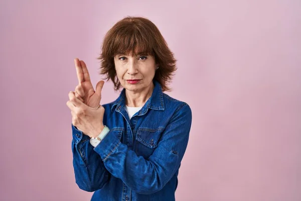 Middle Age Woman Standing Pink Background Holding Symbolic Gun Hand — Stock Photo, Image