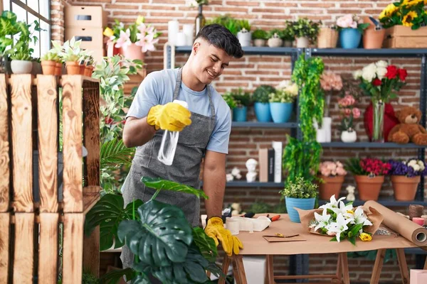 Young hispanic man florist using difusser working at flower shop