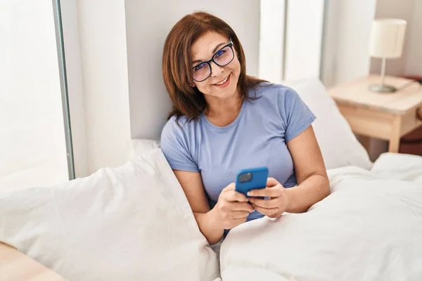 Жінка Середнього Віку Використовуючи Смартфон Сидячи Ліжку Спальні — стокове фото