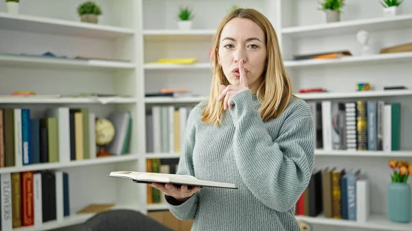 Young Blonde Woman Student Reading Book Doing Silence Gesture Library — 图库照片