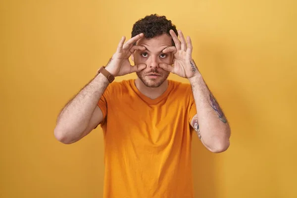 Sarı Arka Planda Dikilen Genç Spanyol Adam Parmaklarıyla Gözlerini Açmaya — Stok fotoğraf