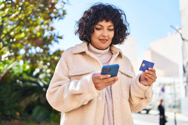 公園でスマートフォンやクレジットカードを使用して若い美しいヒスパニック系女性 — ストック写真