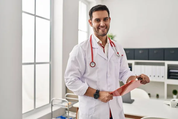 Junger Hispanischer Mann Arztuniform Hält Klemmbrett Klinik — Stockfoto