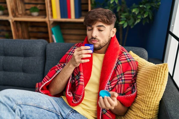 Young Arab Man Smelling Mint Medication Sitting Sofa Home — Stockfoto
