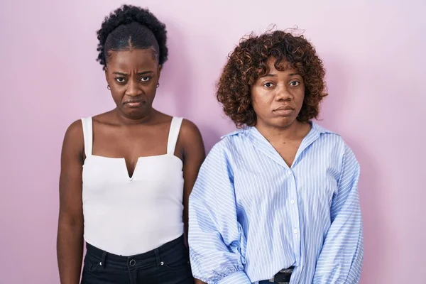 Две Африканские Женщины Стоящие Розовом Фоне Скептически Нервно Хмурясь Расстроены — стоковое фото
