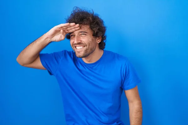 Spaanse Jongeman Die Een Blauwe Achtergrond Staat Erg Blij Glimlachend — Stockfoto