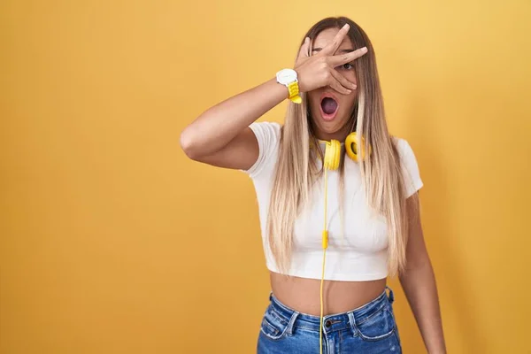 Jovem Loira Sobre Fundo Amarelo Usando Fones Ouvido Espreitando Choque — Fotografia de Stock