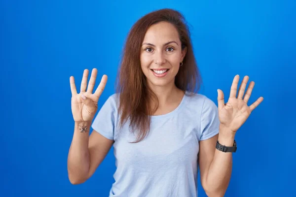 布鲁内特女人站在蓝色的背景上 用9号手指指指指点点 面带微笑 自信而快乐 — 图库照片