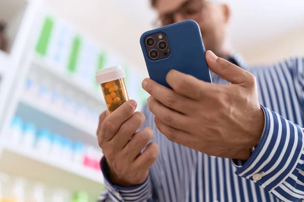 Молодой Латиноамериканец Клиент Помощью Смартфона Держит Бутылку Таблетками Аптеке — стоковое фото