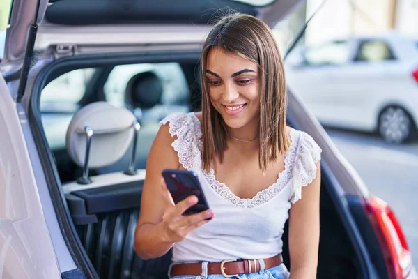 Young Beautiful Hispanic Woman Using Smartphone Sitting Car Trunk Street — Foto de Stock