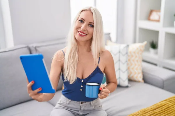 Mladá Blondýna Žena Pomocí Touchpad Pití Kávy Doma — Stock fotografie