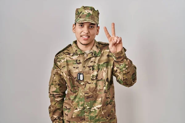 自信と幸せ笑顔ながら カモフラージュ軍の制服を身に着けている若いアラブ人男性が現れ 指数2で指摘します — ストック写真