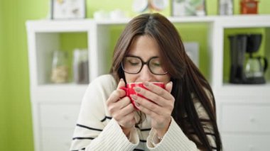 Genç, güzel, İspanyol bir kadın yemek odasında kahve içiyor.