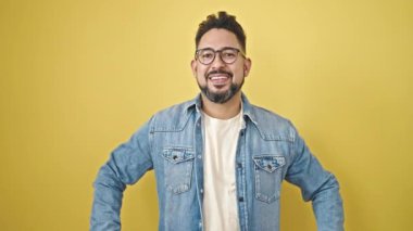 İzole edilmiş sarı arka planda sürpriz bir ifadeyle duran genç latin adam.