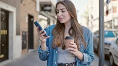 Genç ve güzel İspanyol kadın akıllı telefon kullanıyor. Sokakta kahve içiyor.