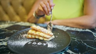 Orta yaşlı İspanyol bir kadın restoranda tatlı niyetine milhoja yiyor.