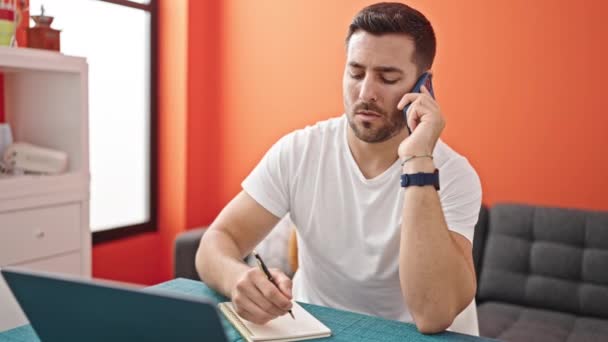 Young Hispanic Man Talking Smartphone Using Laptop Taking Notes Dinning — Stock Video