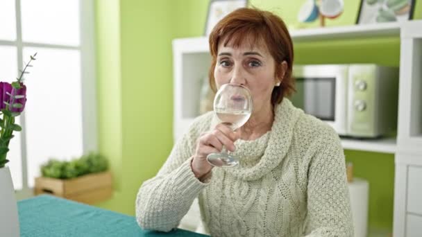 熟女ヒスパニック女性座っています上のテーブルの上に飲む白ワインでダイニングルーム — ストック動画