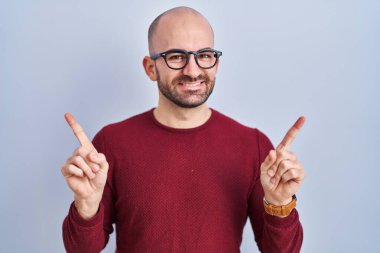 Beyaz arka planda duran, sakallı, gözlüklü, kendine güvenen, farklı yönleri gösteren, kendine güvenen genç, kel bir adam. reklam için kopyalama alanı 