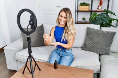 Young woman recording skin care tutorial by smartphone at home