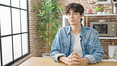 Genç İspanyol adam yemek odasında rahat bir ifadeyle masada oturuyor.