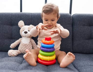 Sevimli İspanyol bebek evdeki kanepede oturmuş basketbol oynuyor.