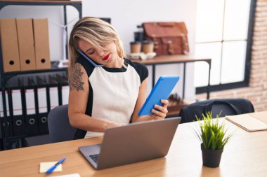 Genç, güzel İspanyol iş kadını. Ofiste dokunmatik ped kullanarak akıllı telefondan konuşuyor.