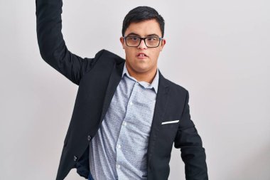 Down sendromlu genç bir İspanyol iş stili giyiyor kızgın ve kızgın yumruğunu kaldırıyor ve öfkeyle bağırıyor. öfke ve agresif konsept. 