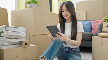 Genç Çinli kadın yeni evinde rahat bir ifadeyle dokunmatik ped kullanıyor.