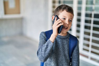 Sarışın çocuk okulda akıllı telefondan konuşuyor.
