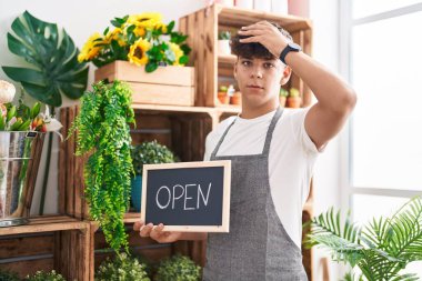 Çiçekçide çalışan İspanyol genç elinde açık tabela tutarken gergin ve hayal kırıklığına uğramış, şaşırmış ve sinirli bir yüz ifadesi vardı. 