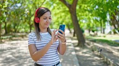 Ortadoğulu kadın parkta kulaklık takıyor.