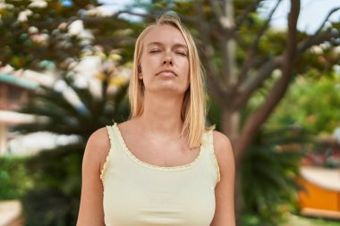 Young blonde woman breathing at park