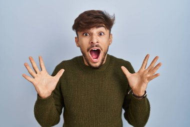 Mavi arka planda duran sakallı bir Arap çılgın ve başarıyı kolları açık ve gözleri açık heyecanla haykırarak kutluyor. Kazanan konsept 