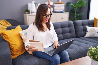 Evde dizüstü bilgisayar kullanan genç ve güzel bir İspanyol kadın.