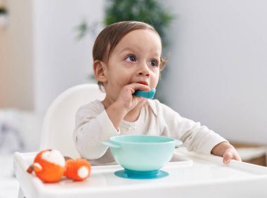 Sevimli İspanyol çocuk sandalyeye oturmuş yatak odasında kaşık emiyor.