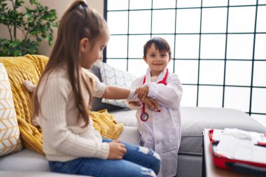 Sevimli kız ve erkek doktor üniforması giyip evde sargı bezi takıyorlar.