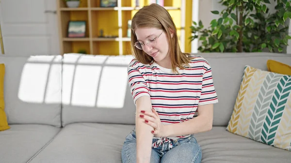 Joven Mujer Rubia Rascarse Los Brazos Sentado Sofá Casa —  Fotos de Stock