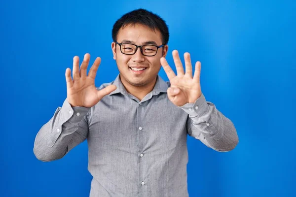 Młody Chińczyk Stojący Nad Niebieskim Tle Pokazuje Wskazuje Palcami Numer — Zdjęcie stockowe