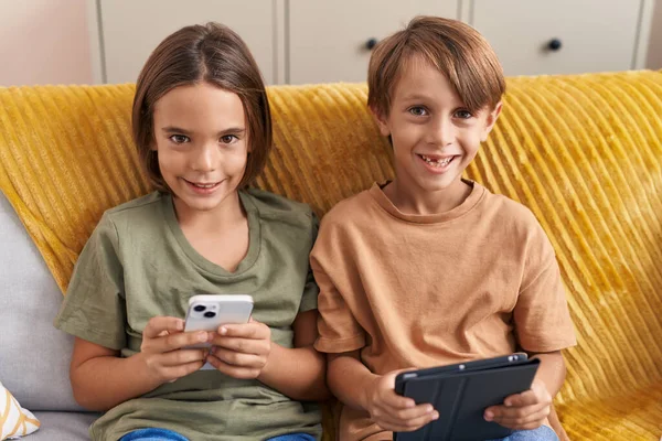 Adoráveis Meninos Usando Smartphone Touchpad Sentado Sofá Casa — Fotografia de Stock