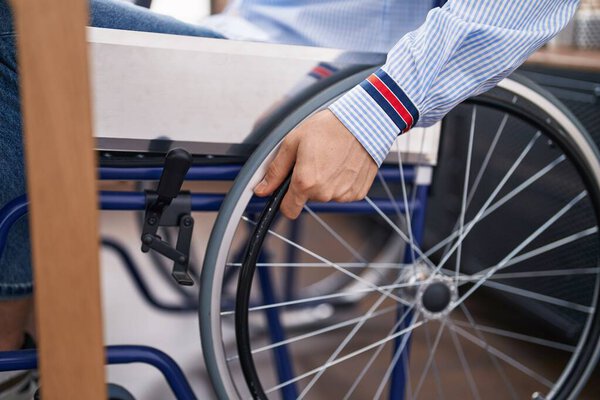 Молодой кавказский бизнесмен сидит на инвалидной коляске в офисе