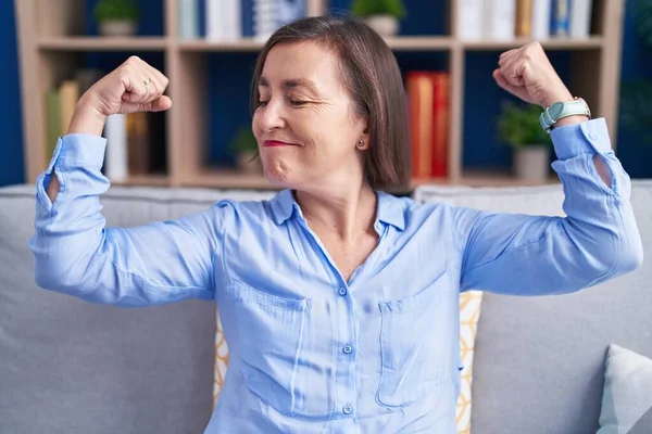 Middle Age Hispanic Woman Sitting Sofa Home Showing Arms Muscles — Stock Photo, Image