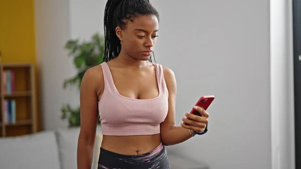 Afroamerikanerin Trägt Sportbekleidung Mit Smartphone Und Ernstem Gesichtsausdruck Hause — Stockfoto