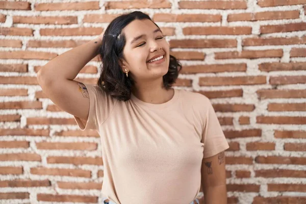 Jonge Spaanse Vrouw Staat Bakstenen Muur Glimlachend Zelfverzekerd Aanraken Haar — Stockfoto