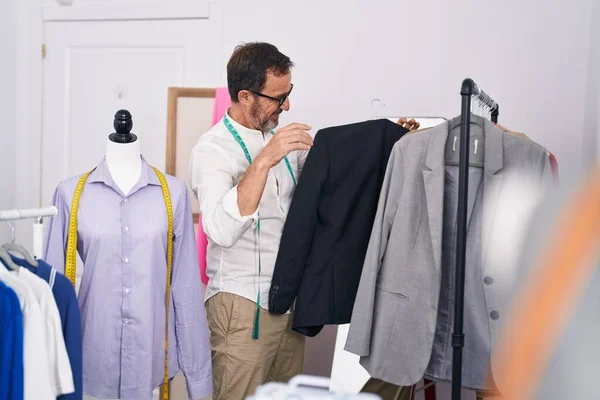 中年男人裁缝笑着自信地把衣服架在裁缝店的架子上 — 图库照片