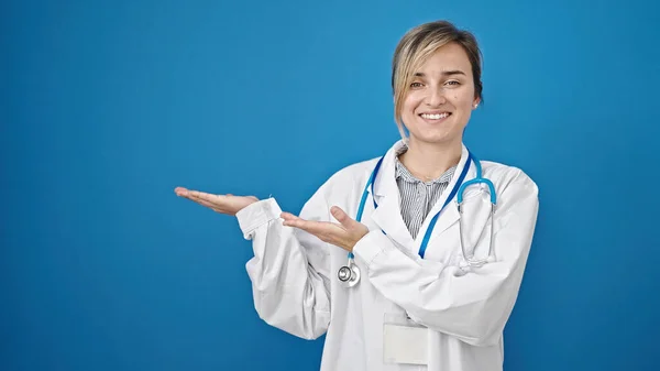 Junge Blonde Ärztin Lächelt Selbstbewusst Und Präsentiert Sich Vor Isoliertem — Stockfoto
