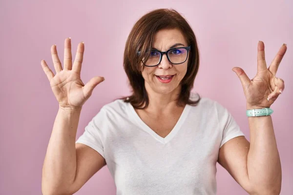 中年惊慌失措的女人站在粉红的背景上 用八号手指指指着 面带微笑 自信而快乐 — 图库照片