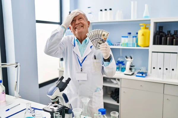 Starszy Naukowiec Siwymi Włosami Pracujący Laboratorium Trzymający Dolary Zestresowany Sfrustrowany — Zdjęcie stockowe