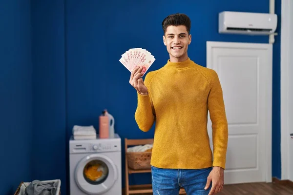Young Hispanic Man Laundry Room Holding Shekels Looking Positive Happy — Stock Photo, Image